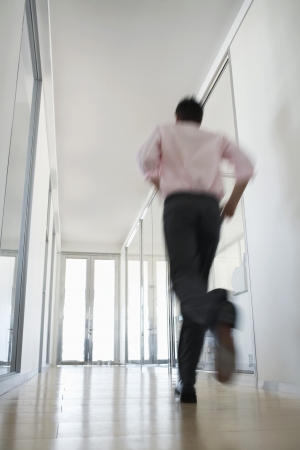 Businessman Running in Corridor low angle back view.の写真素材