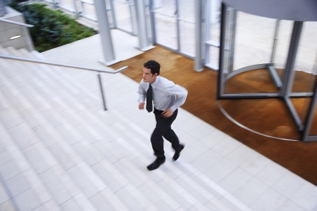 Businessman running up stairs in office lobbyの写真素材