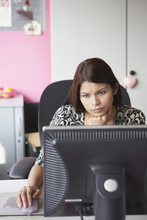 Office worker using computer sitting behind desk elevated viewの写真素材