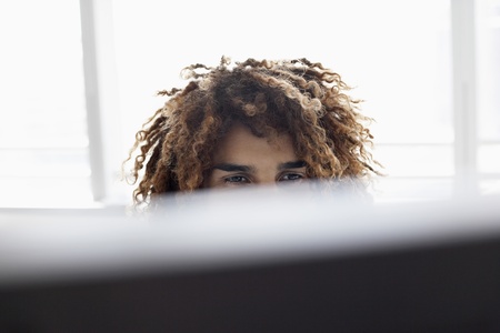 Young man using computer sitting at desk close up