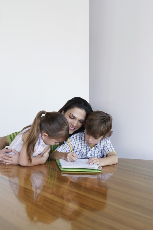 Mother assisting son (7-9) and daughter (5-6) doing homeworkの写真素材