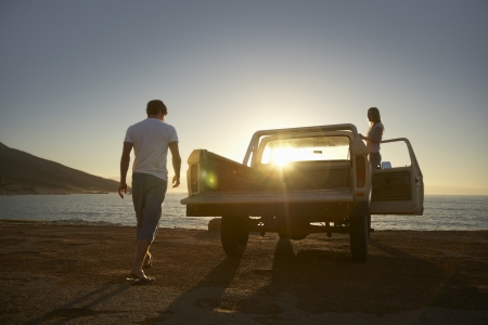 Young couple by van parked in front of ocean