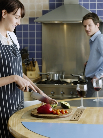 Young couple in kitchen woman chopping vegetablesの写真素材