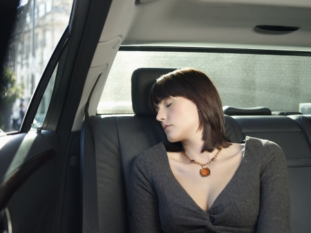Mid adult woman sleeping at back seat of carの写真素材