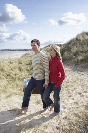 Couple holding hands walking on sand duneの写真素材