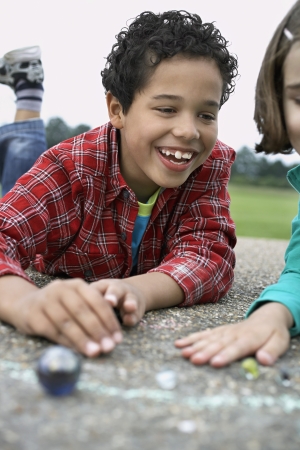 Boy and girl (7-9) playing marbles in playgroundの写真素材