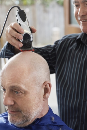 Barber shaving mans head in barber shopの写真素材