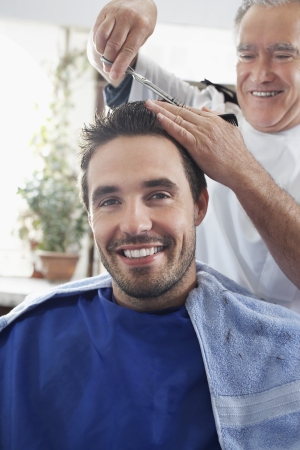 Barber cutting mans hair in barber shopの写真素材