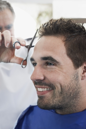 Barber cutting mans hair in barber shop close-upの写真素材