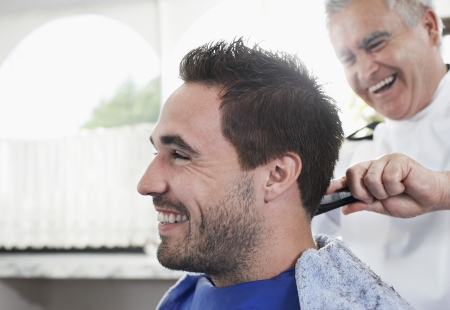 Barber cutting mans hair in barber shop close-upの写真素材