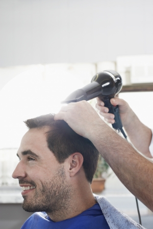 Barber drying mans hair in barber shopの写真素材