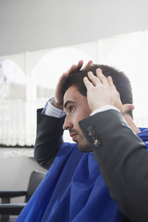 Business man checking freshly cut hair in barbersの写真素材