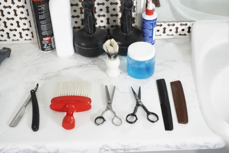 Scissors combs razor brush and hair products on counter in barber shop