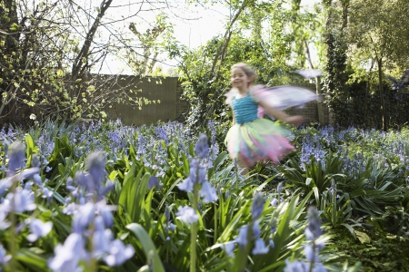 Young girl (5-6) running in flower garden wearing fairy costume motion blurの写真素材