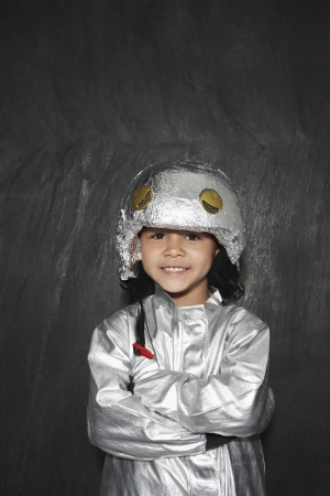 Portrait of young boy (5-6) in astronaut costume crossed arms smiling studio shotの写真素材