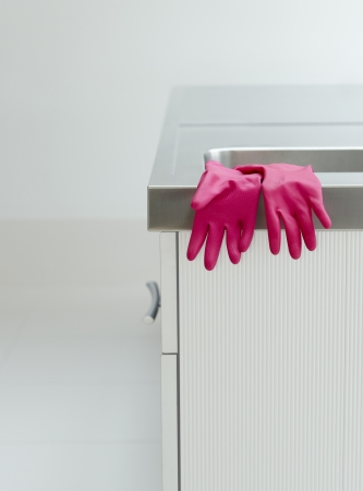 Pink rubber gloves on edge of sinkの写真素材