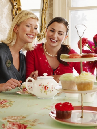 Two young women sitting at dining table portraitの写真素材