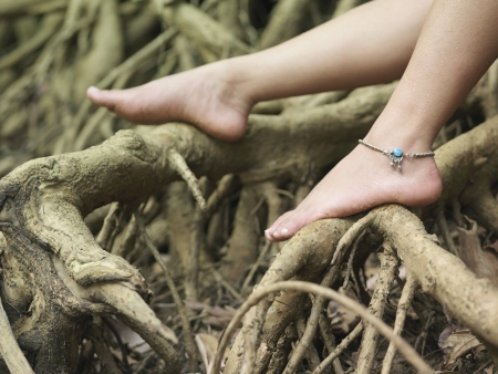 Young woman sitting on tree roots close-up on footの写真素材