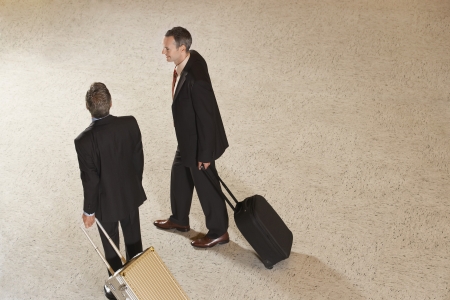Two business men pulling suitcases in lobbyの写真素材