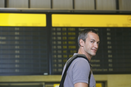 Traveller in front of flight status board in airportの写真素材