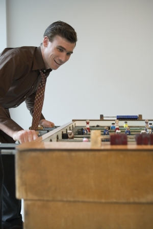 Young man playing table football in game roomの写真素材