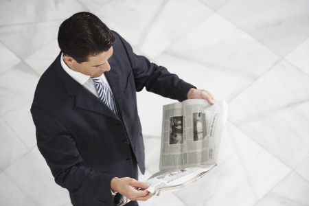 Business man reading newspaper indoorsの写真素材