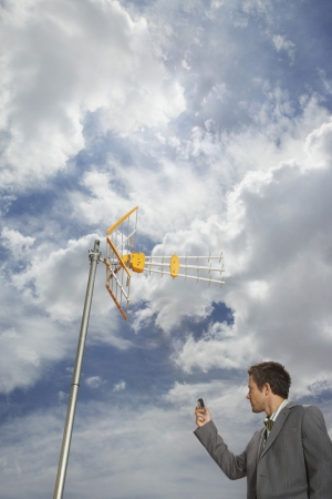 Business man pointing cell phone at aerialの写真素材