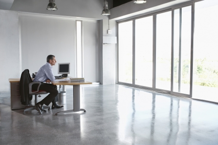 Man sitting at desk in empty office buildingの写真素材