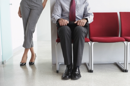 Woman standing beside man on chairs in corridorの写真素材