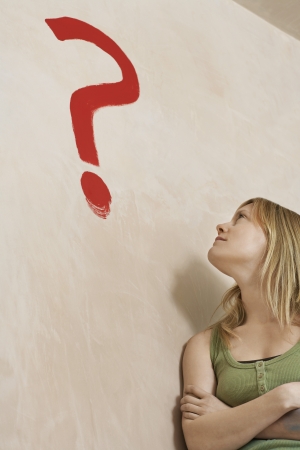 Woman leaning against wall with painted question markの写真素材
