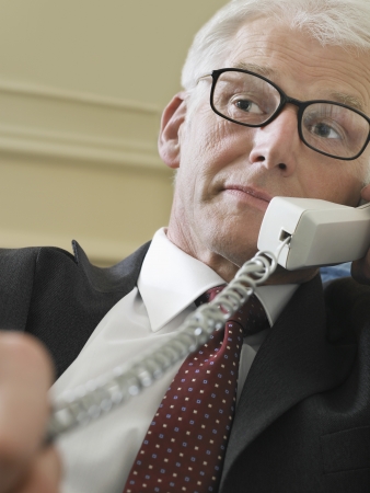 Business man using phone sitting on sofa close-up low angle viewの写真素材