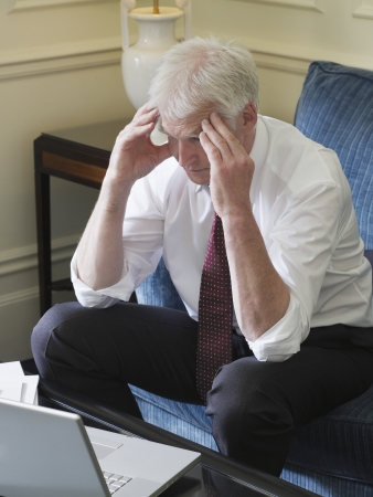 Business man using laptop sitting on sofa elevated viewの写真素材