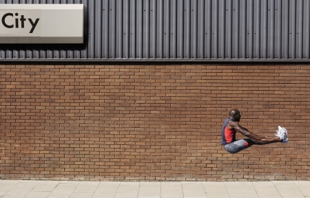 Man jumping by wall with 'city' written on itの写真素材