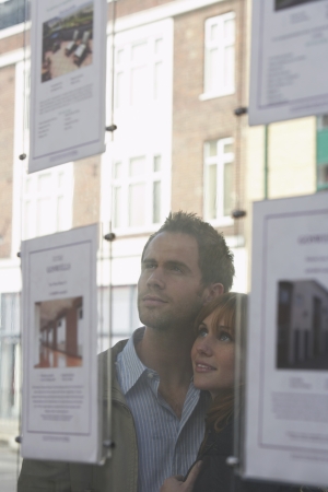 Couple looking through window at estate agentsの写真素材