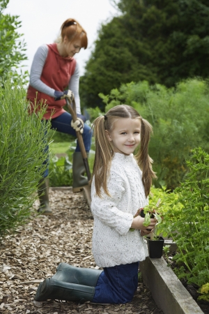 Girl (5-6) gardening with mother in countrysideの写真素材