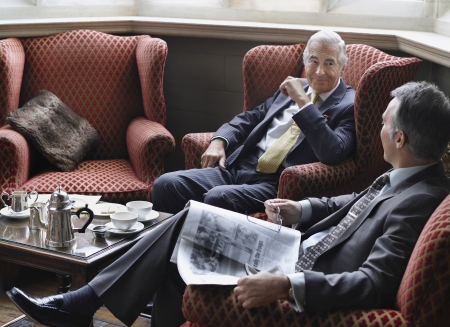 Two business men sitting in lobby talking one holding newspaperの写真素材