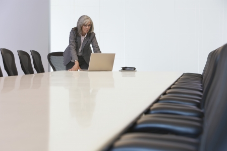 Business woman using laptop in board roomの写真素材