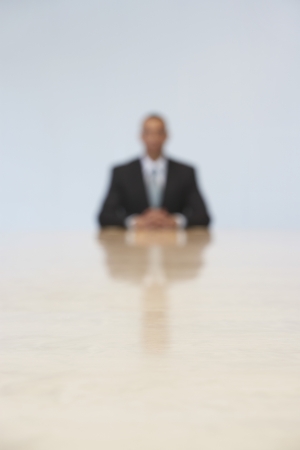 Business man sitting at end of conference table (defocused)の写真素材