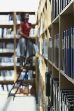 Office worker standing on ladder in file storage room selective focus side viewの写真素材