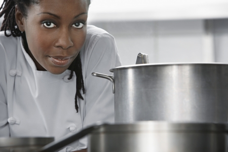 Female chef near saucepan in kitchen portraitの写真素材