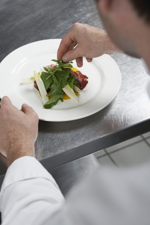 Male chef preparing salad in kitchenの写真素材