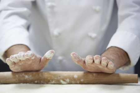 Chef rolling dough using rollingpin close-upの写真素材