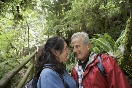 Senior man and middle-aged woman in forest looking in eyes smilingの写真素材