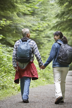 Couple walking along forest road rear viewの写真素材