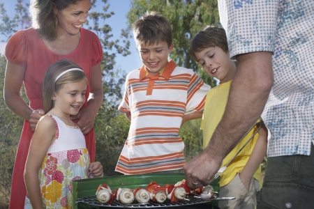 Family with three children (6-11) grilling in gardenの写真素材