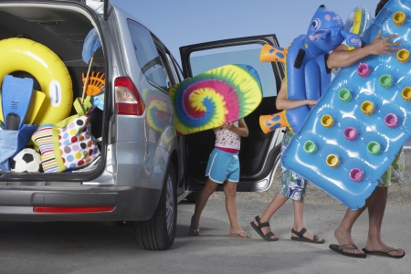 Father and two children (6-11) unloading beach accessories from carの写真素材