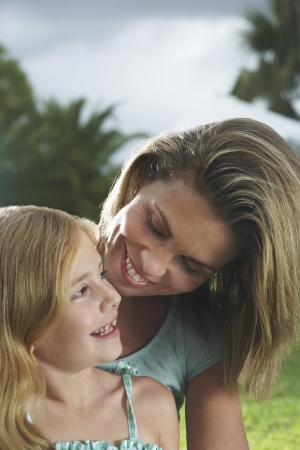 Mother and daughter (5-6) talking and laughing outdoorsの写真素材