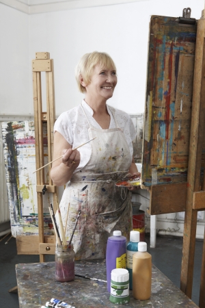 Mature female artist painting at easel in art studiocanvas in studioの写真素材
