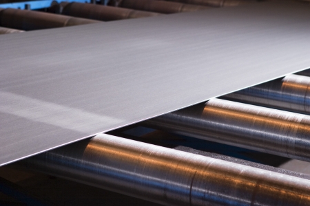 Continuous sheet of metallic material being fed through machineの写真素材