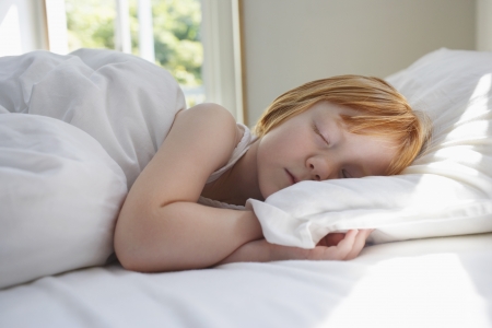 Close-up of girl (5-6) sleeping in bedの写真素材